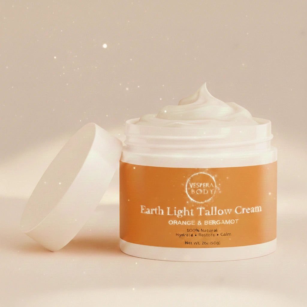 Open jar of Earth Light Tallow Cream in the Orange & Bergamot variant showing its soft whipped tallow texture under warm neutral light with subtle celestial reflections.